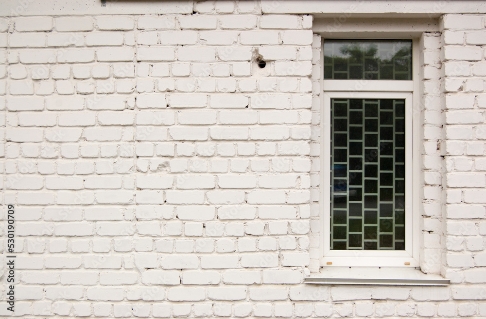 Brick white painted wall with a narrow glazed window Brick white painted wall with a narrow glazed window