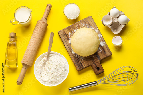 Composition with ingredients for baking and raw dough on yellow background