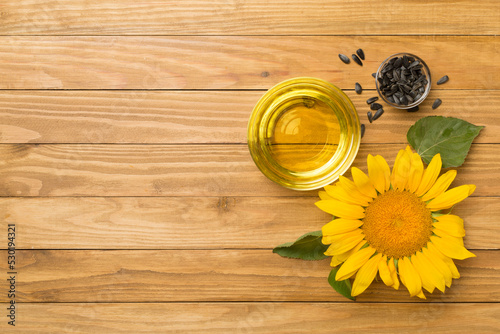Sunflower oil, seeds and flower on wooden background, top view