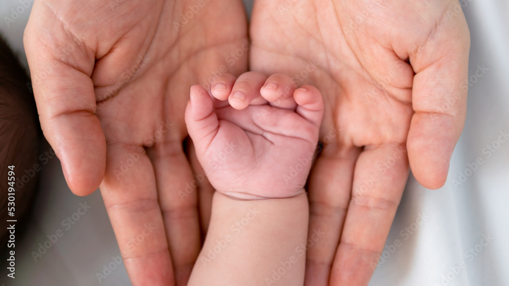 Close up little tiny baby hand palm over a mother hands. Peace calm newborn Close up little tiny baby hand palm over a mother hands. Peace calm newborn