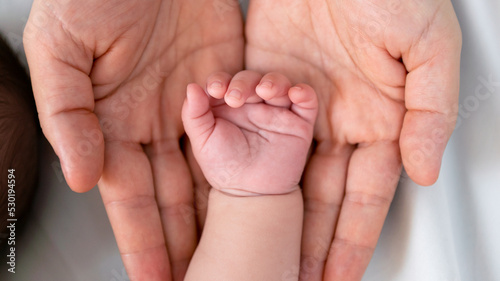 Close up little tiny baby hand palm over a mother hands. Peace calm newborn