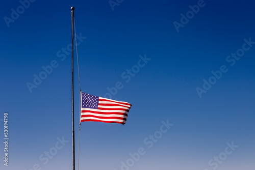 American flag blowing on blue sky at half mast in New York, september 11, USA photo