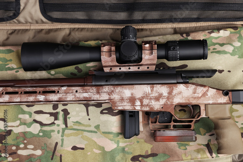 Modern powerful sniper rifle with telescopic sight on camouflage fabric, top view