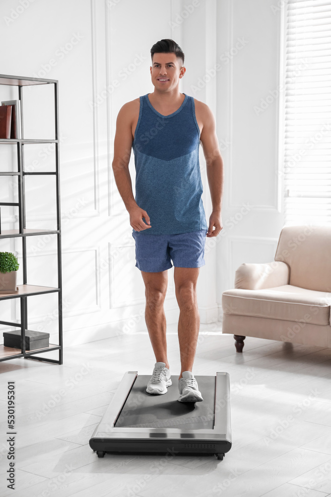 Sporty man training on walking treadmill at home Sporty man training on walking treadmill at home