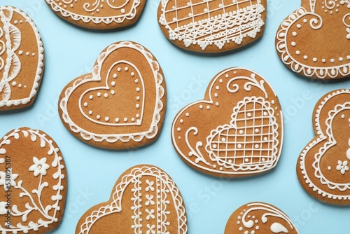 Tasty heart shaped gingerbread cookies on light blue background, flat lay