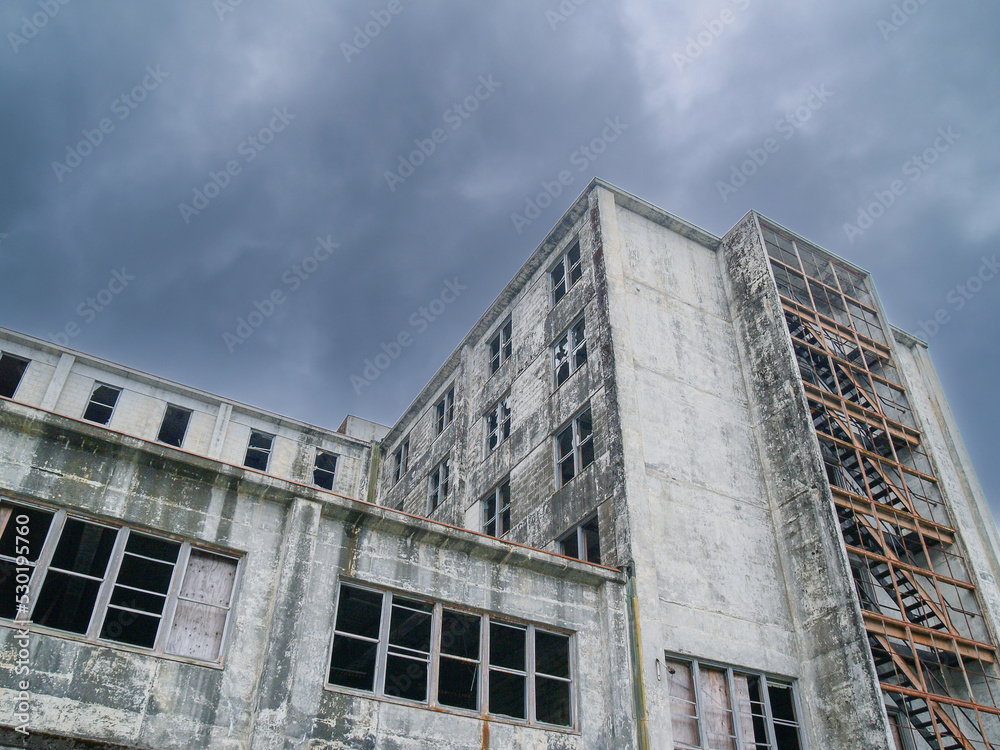 Dark ominous clouds and abandonment of old concrete industrial building