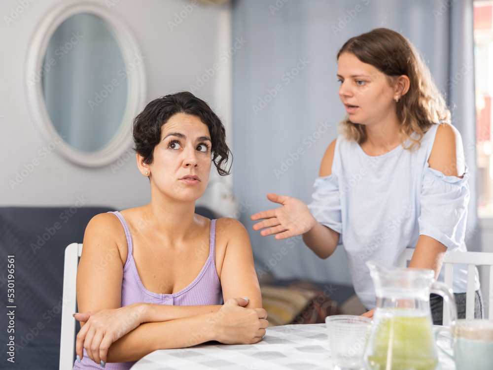 Fototapeta premium Young bored or offended woman ignoring her wife talking, LGBTQ family problems concept