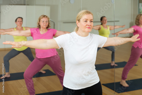 Mature European women are doing warrior II pose