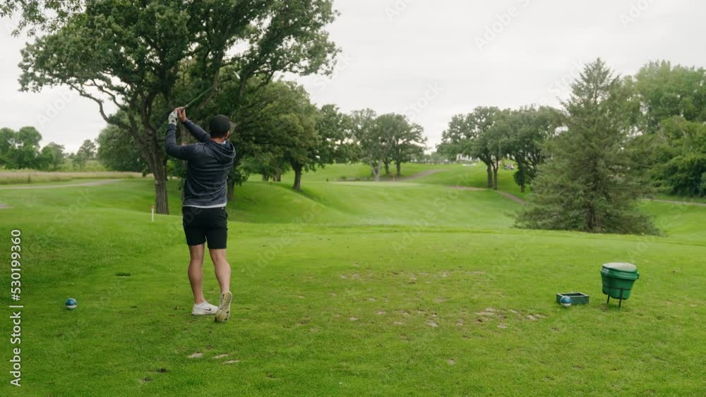 golfer swinging an iron and hitting a golf ball on a par 3 hole