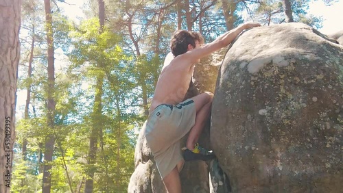 shirtless teenage boy topping a boulder in pine forrest fontainebleau sun flares photo