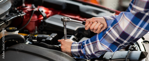 Female auto mechanic unscrewing a nut to replace a car spark plug.