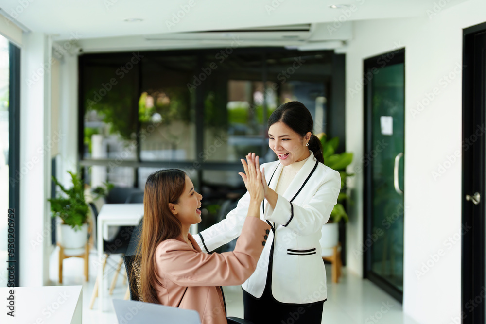 two female employees posing together after sales hit their targets.