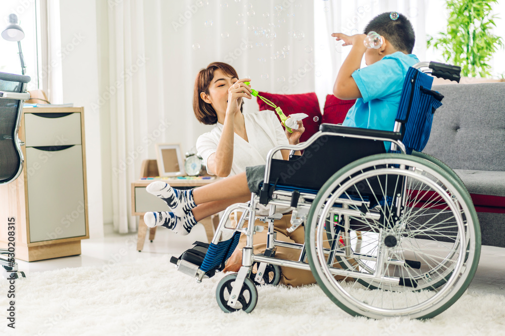 Portrait of enjoy happy love family asian mother playing and carer helping look at disabled son child sitting in wheelchair moments good time at home.disability care concept Portrait of enjoy happy love family asian mother playing and carer helping look at disabled son child sitting in wheelchair moments good time at home.disability care concept