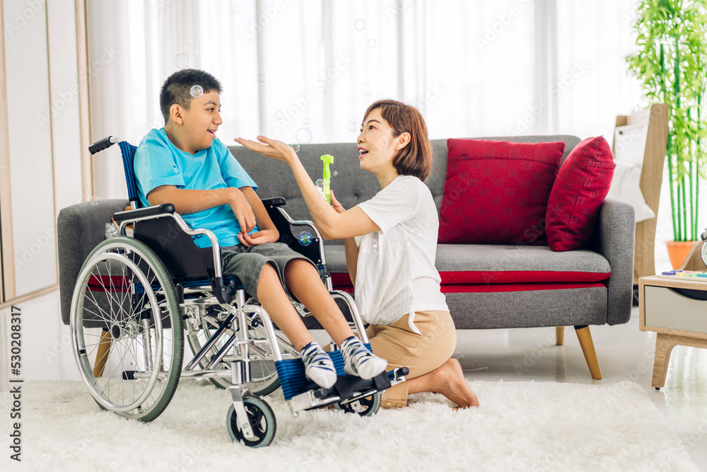 Portrait of enjoy happy love family asian mother playing and carer helping look at disabled son child sitting in wheelchair moments good time at home.disability care concept Portrait of enjoy happy love family asian mother playing and carer helping look at disabled son child sitting in wheelchair moments good time at home.disability care concept