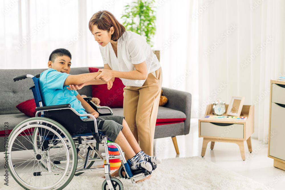 Portrait of enjoy happy love family asian mother playing and carer helping look at disabled son child sitting in wheelchair moments good time at home.disability care concept Portrait of enjoy happy love family asian mother playing and carer helping look at disabled son child sitting in wheelchair moments good time at home.disability care concept