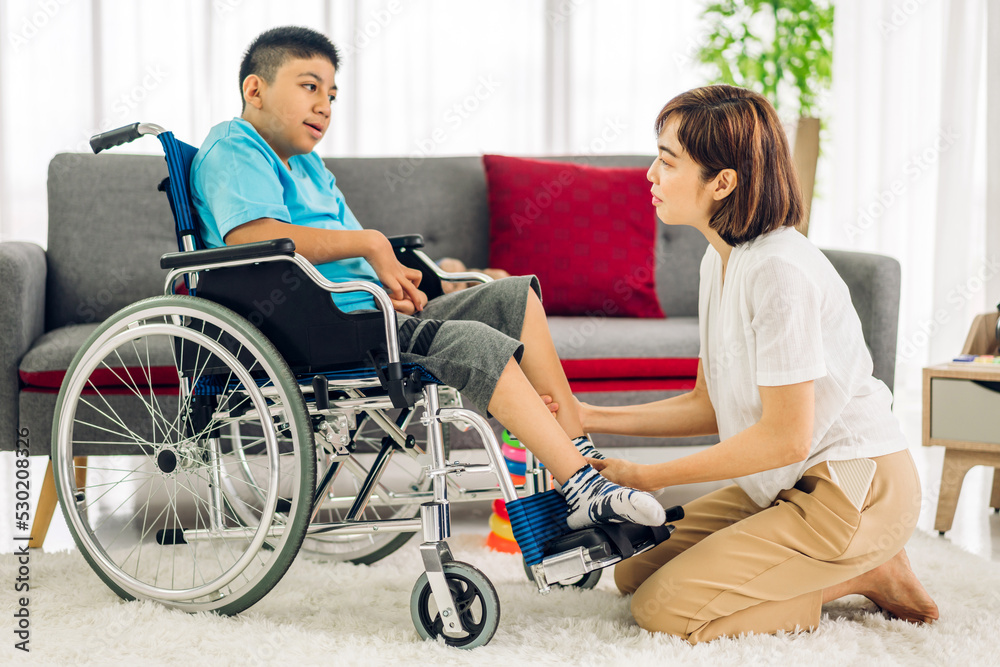 Portrait of enjoy happy love family asian mother playing and carer helping look at disabled son child sitting in wheelchair moments good time at home.disability care concept	
