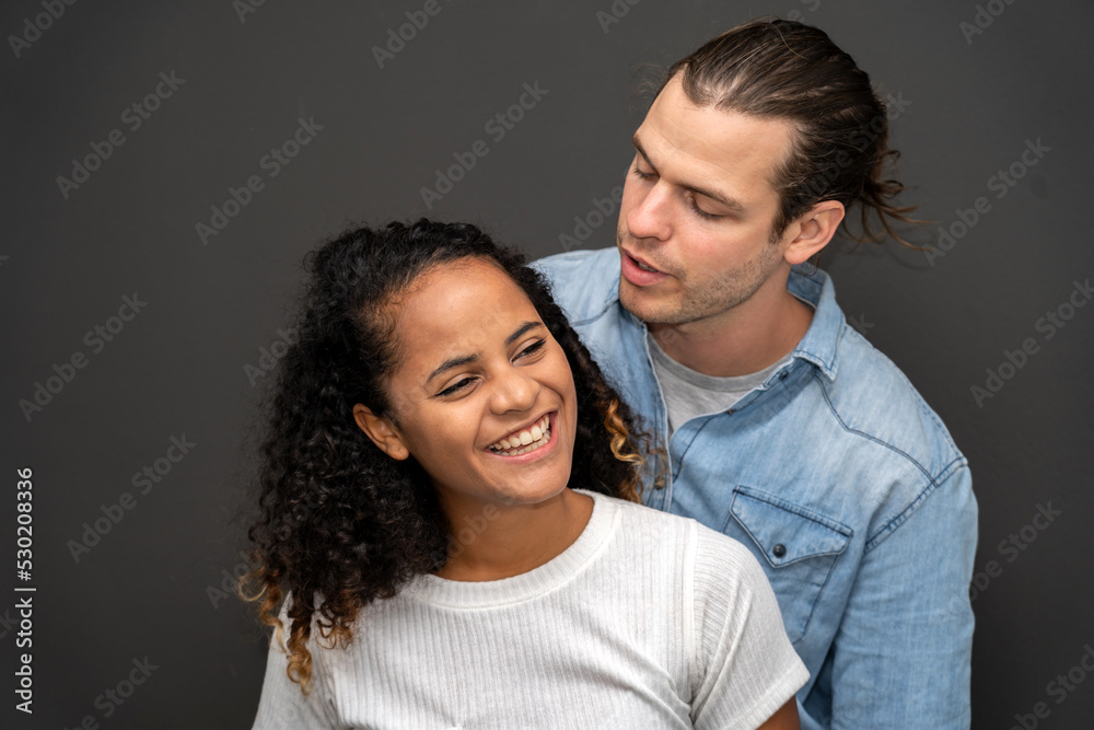 Romantic young happy couple caucasian man and african american woman smile and have fun together in valentine day on black background Romantic young happy couple caucasian man and african american woman smile and have fun together in valentine day on black background