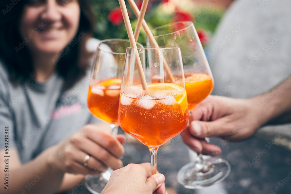 Friends raise glasses of Venetian Spritz at a home party. Front view. Friends raise glasses of Venetian Spritz at a home party. Front view.