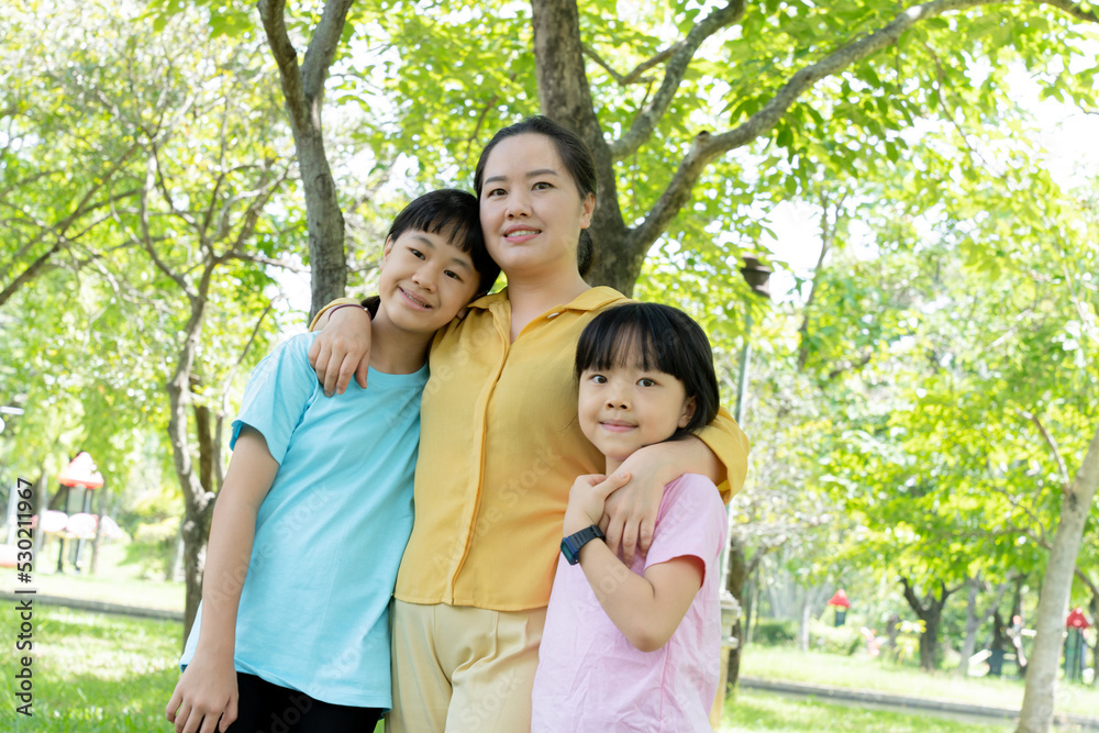 Portrait of young mother and two daughters in blooming spring green park. Mothers day holiday or womans day concept Portrait of young mother and two daughters in blooming spring green park. Mothers day holiday or womans day concept