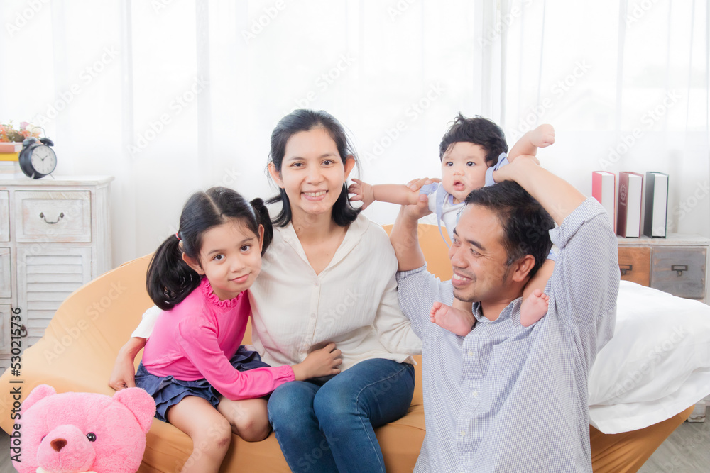 Selective focus Asian happy family laughing and hugging with love and warmth, smiling parents and eldest sister with toddler having fun together in holiday, family enjoying free time. Selective focus Asian happy family laughing and hugging with love and warmth, smiling parents and eldest sister with toddler having fun together in holiday, family enjoying free time.