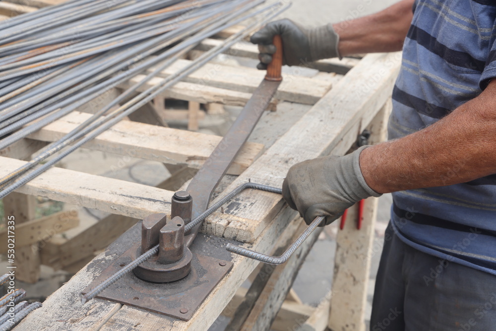 Hands of a worker at work at the armature bending machine. Rebars with