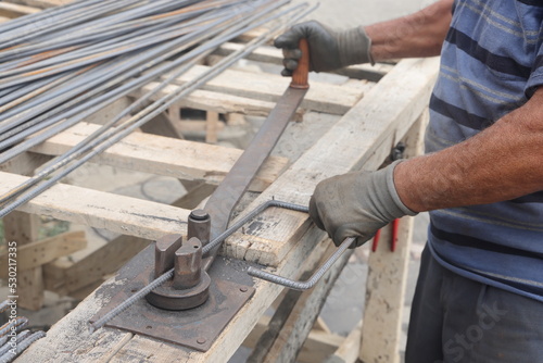 Hands of a worker at work at the armature bending machine. Rebars with rebar bending machine in the site. Worker using bending rebar machine for reinforcement in the construction work.