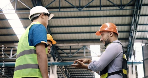 Manager, staff or boss to talking, discussion with worker, employee. Group of people in warehouse, factory with safety helmet, vest. Concept for industry, job, meeting, work training and teamwork.
 photo