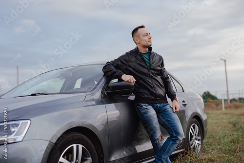 Handsome stylish man standing near his car at the field © antgor