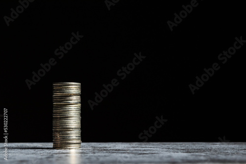 Stack of coins on grey table and black background. Start-up capital concept with copy space.