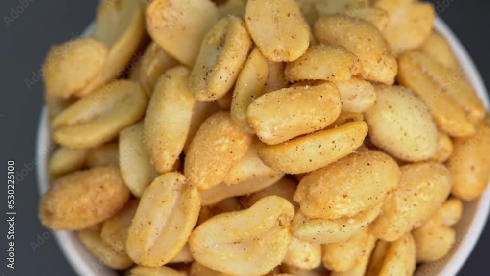 Roasted peanuts rotate in a bawl, peanuts without shells, ground nuts. Spiced peanuts spin close up. Bunch of nuts with cheese sprinkles are poured. Food for beer. Delicious and nutritious snacks. Roasted peanuts rotate in a bawl, peanuts without shells, ground nuts. Spiced peanuts spin close up. Bunch of nuts with cheese sprinkles are poured. Food for beer. Delicious and nutritious snacks.