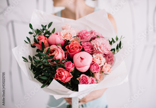 Very nice young woman holding big and beautiful bouquet of fresh peony, roses, carnations, pistachio flowers in pink colors, cropped photo, bouquet close up
