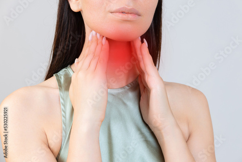 Sore throat in flu season. Young asian woman touching her neck and feeling pain in throat in the bedroom at home. photo