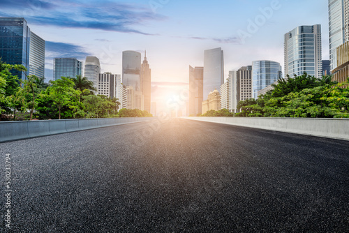 Straight asphalt road and modern city skyline with buildings in Guangzhou at sunset, China.