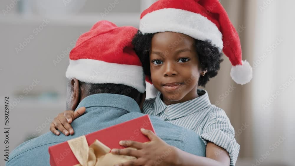 Close-up happy pretty kid girl wear santa hat hugging dad looking at camera holding new year box celebrating christmas enjoying holiday with family cute loving daughter rejoices in gift embrace father