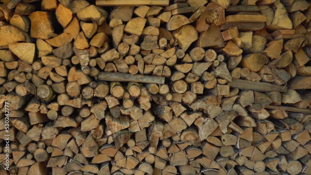 Woodpile of a split tree in close-up. Logs of firewood, chopped and stacked. Stack of firewood for the fireplace. Concept of wood, renewable energy natural resources.