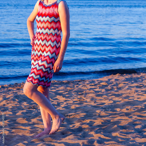 A woman in a red and blue knitted dress with a Missoni zigzag pattern on the beach in summer photo