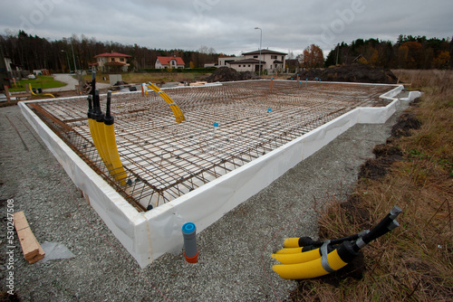 Reinforcement of foundation slab of private house. Preparation for pouring concrete foundation for house. Plinth is insulated with foam. Pavement is strewn with rubble.