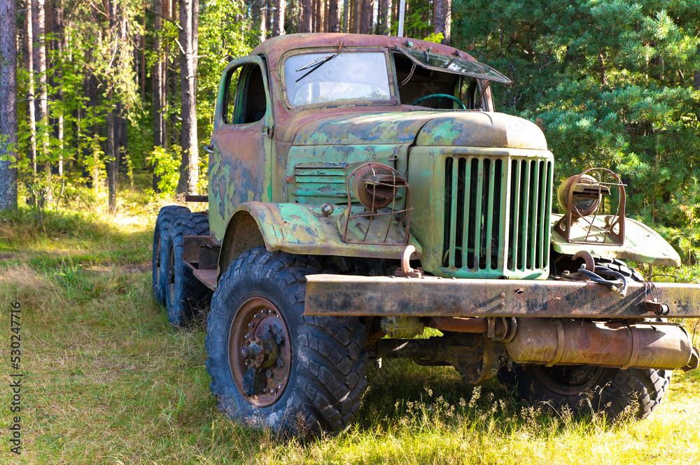 An old large truck with a rusty cab and broken windows