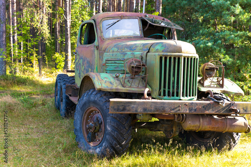 An old large truck with a rusty cab and broken windows