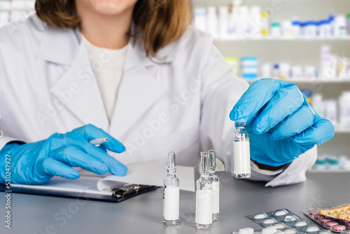 Female doctor in medical gloves showing pharmacy ampoules with medication