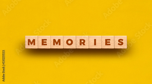 Memories word written on wooden blocks with yellow background