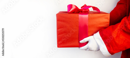 Santa Claus hand holding a Christmas gift box.Christmas. Red background.