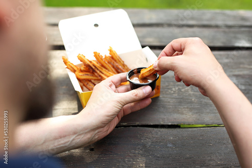 Eating churros, traditional fried dessert from Spain, Portugal. Thin and long sweet delicacy, served with hot chocolate.