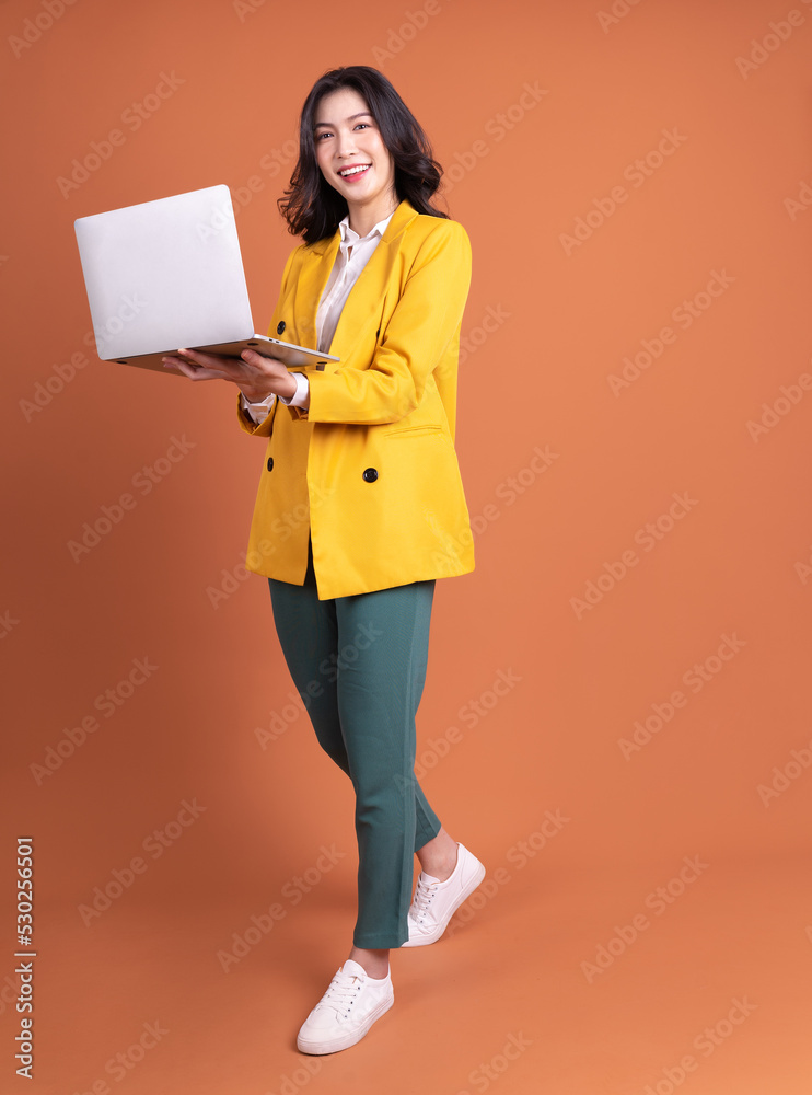 Full length photo of young Asian woman using laptop on background Full length photo of young Asian woman using laptop on background