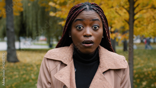 Close-up stunned african american woman standing outdoor looking at camera with eyes wide open and mouth feeling shock surprise from unexpected news amazed young female shocked expression feels wonder © Yuliia