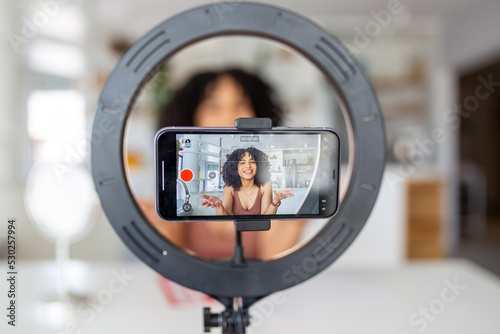 Young female influencer using her smart phone for filming a vlog post.