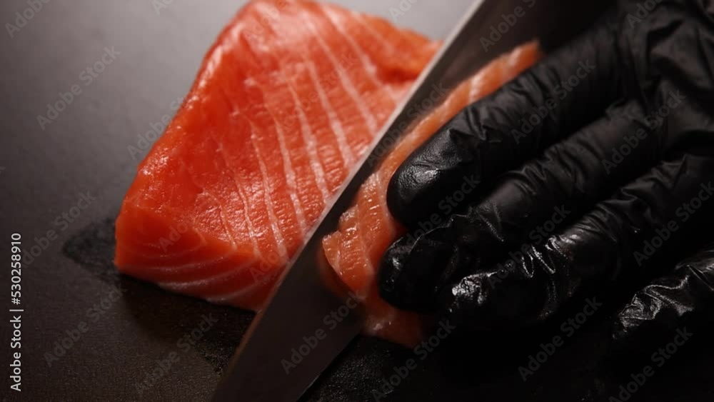 Chef slicing salmon close up. Raw fish on cutting board.