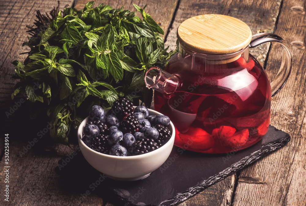 Teapot of fruit tea with mint leaves and berries. Decaffeinated tea
