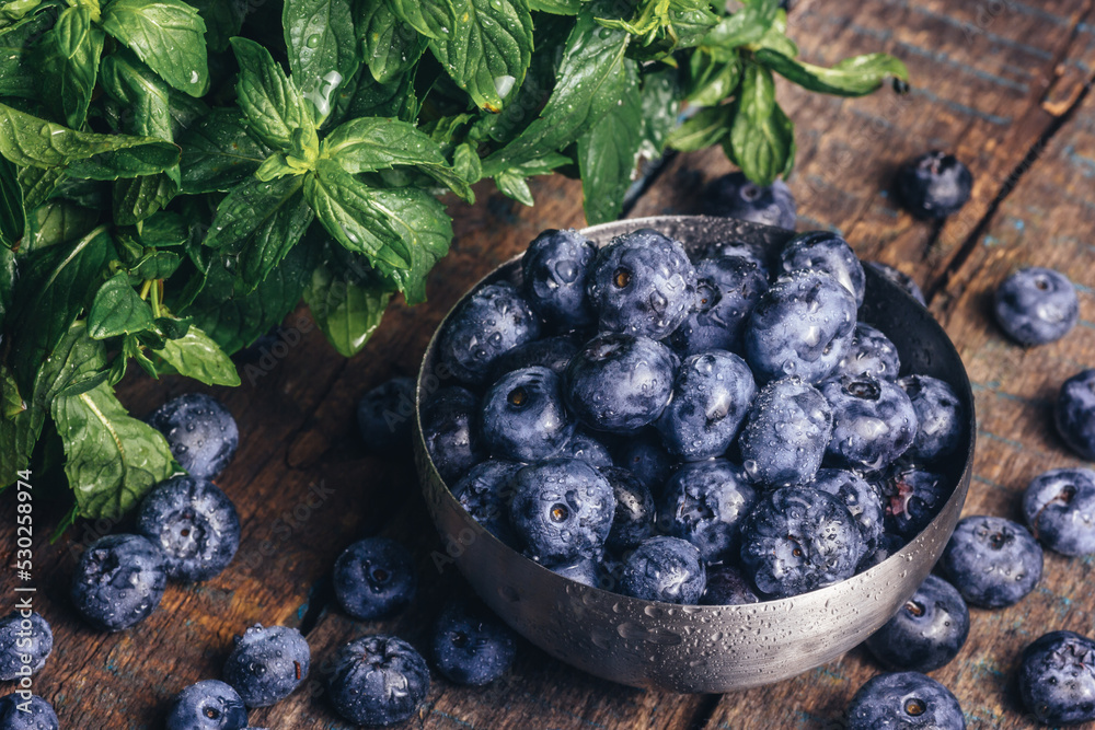 Bowl of delicious fresh blueberries with green leaves. Healthy food concept