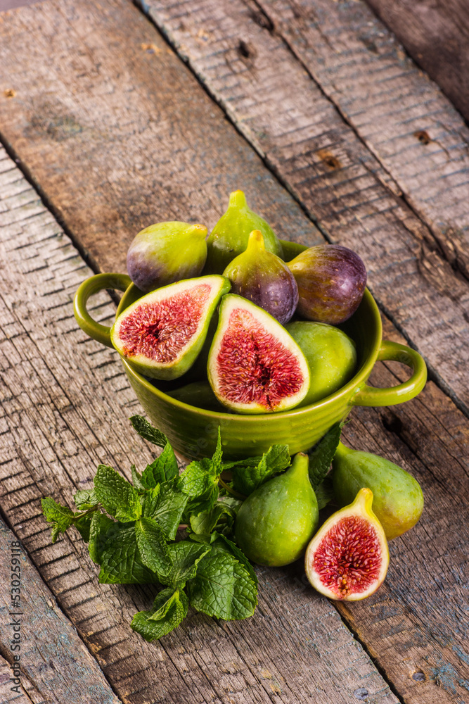 Bowl with fresh raw green figs on wooden background